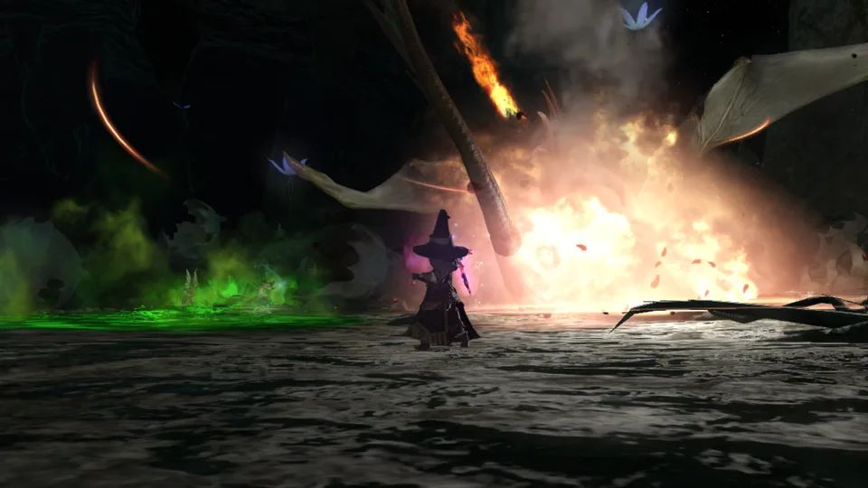 A black mage in a pointed hat stands in a dark cave as fire and green poison effects burst around a dragon with spread wings.