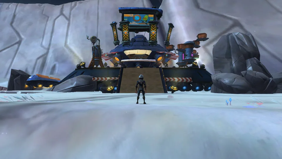 A lone player character stands on a snowy slope facing a large blue industrial outpost with a screen on top.