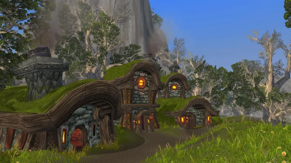 Grass-roofed stone and timber houses on a dirt path beneath a cliff in the Twilight Highlands.